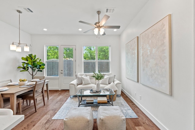 living room with ceiling fan with notable chandelier and wood-type flooring