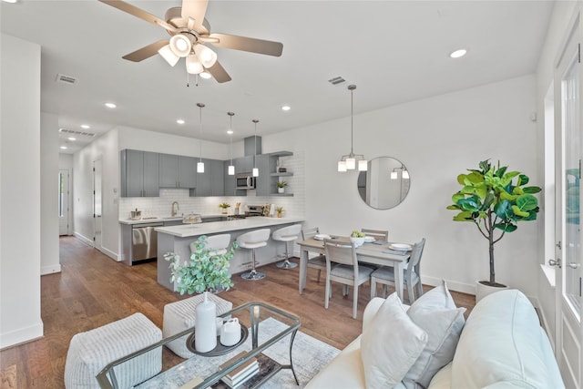 living room featuring ceiling fan, sink, and dark hardwood / wood-style floors