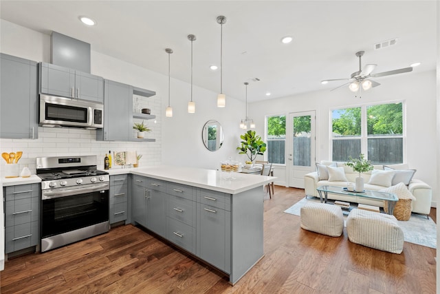 kitchen featuring kitchen peninsula, tasteful backsplash, stainless steel appliances, dark wood-type flooring, and gray cabinets