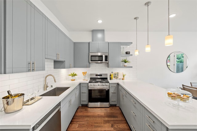 kitchen with decorative backsplash, appliances with stainless steel finishes, kitchen peninsula, sink, and pendant lighting