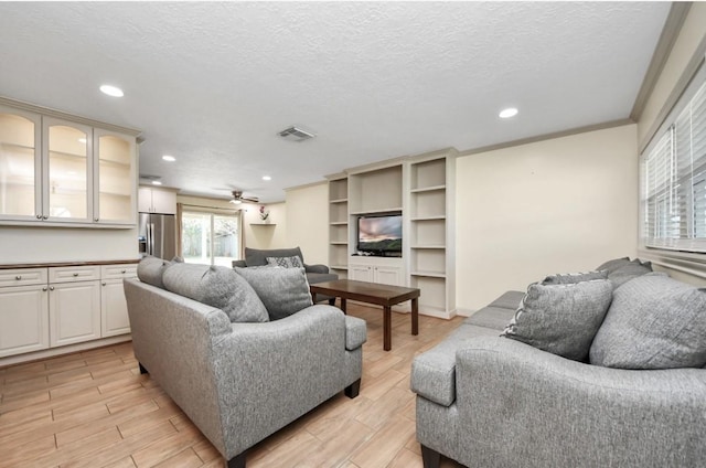 living room featuring a textured ceiling, ceiling fan, and crown molding