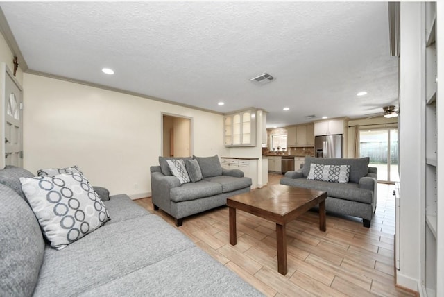 living room featuring a textured ceiling, ceiling fan, and crown molding