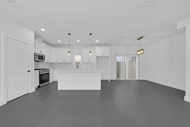 kitchen with white cabinets, a kitchen island, appliances with stainless steel finishes, and pendant lighting