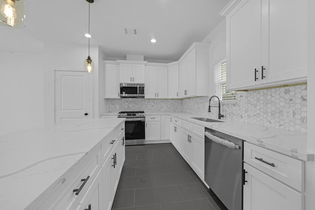 kitchen featuring backsplash, stainless steel appliances, sink, pendant lighting, and white cabinets