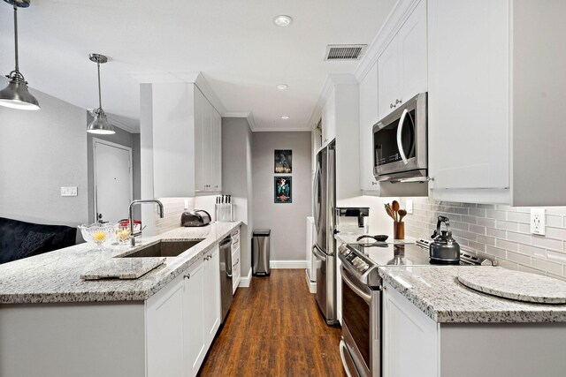 kitchen with light stone countertops, stainless steel appliances, sink, white cabinets, and hanging light fixtures