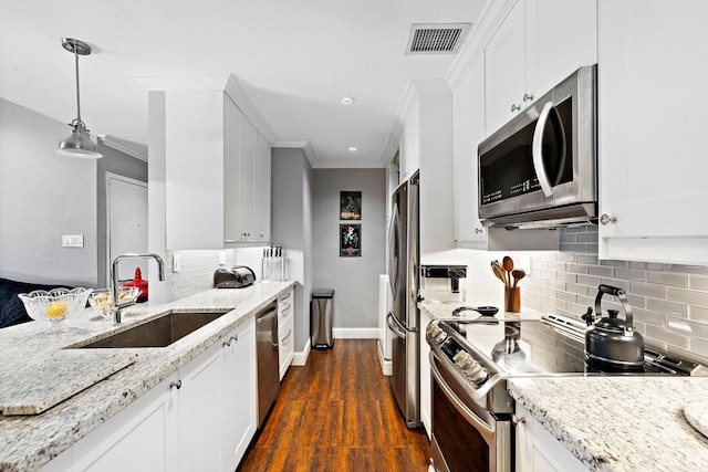 kitchen with light stone counters, stainless steel appliances, sink, pendant lighting, and white cabinetry