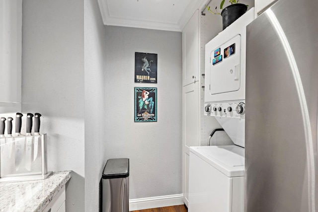 clothes washing area with stacked washer / dryer, crown molding, and wood-type flooring