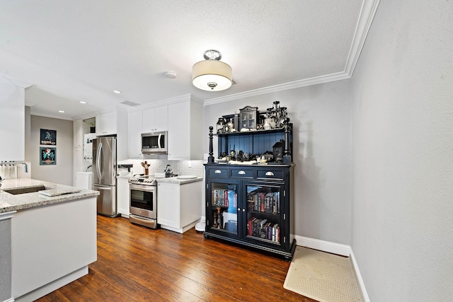 kitchen with appliances with stainless steel finishes, light stone counters, dark wood-type flooring, sink, and white cabinets