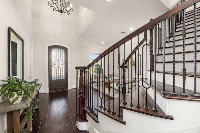 entrance foyer featuring dark hardwood / wood-style flooring, ornamental molding, and an inviting chandelier