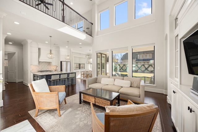 living room featuring ceiling fan, dark hardwood / wood-style floors, a high ceiling, and ornamental molding