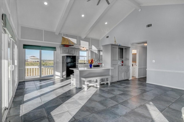 kitchen with black refrigerator, a kitchen bar, beam ceiling, high vaulted ceiling, and gray cabinets