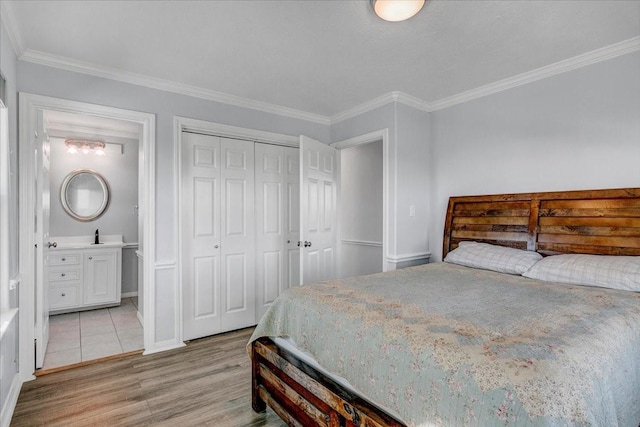 bedroom with light wood-type flooring, crown molding, sink, connected bathroom, and a closet