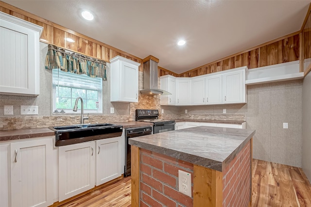 kitchen featuring black appliances, sink, wall chimney exhaust hood, a kitchen island, and white cabinetry