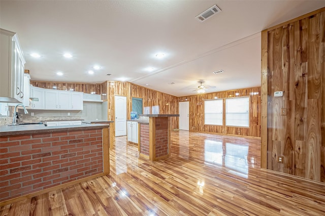 kitchen with kitchen peninsula, ceiling fan, sink, light hardwood / wood-style flooring, and white cabinetry