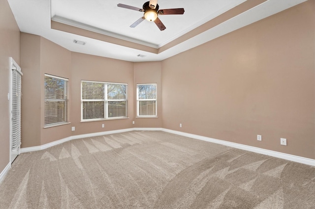 unfurnished room with a raised ceiling, ceiling fan, crown molding, and carpet flooring