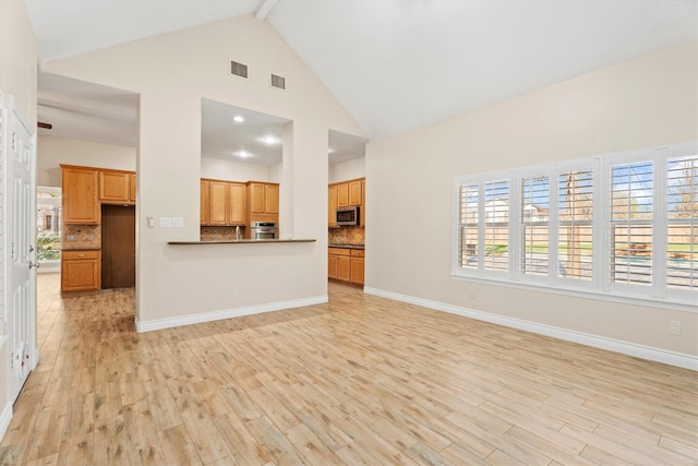 unfurnished living room featuring high vaulted ceiling, beam ceiling, and light wood-type flooring