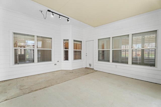 unfurnished sunroom with rail lighting