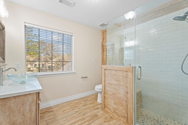 bathroom featuring toilet, a shower with door, and vanity