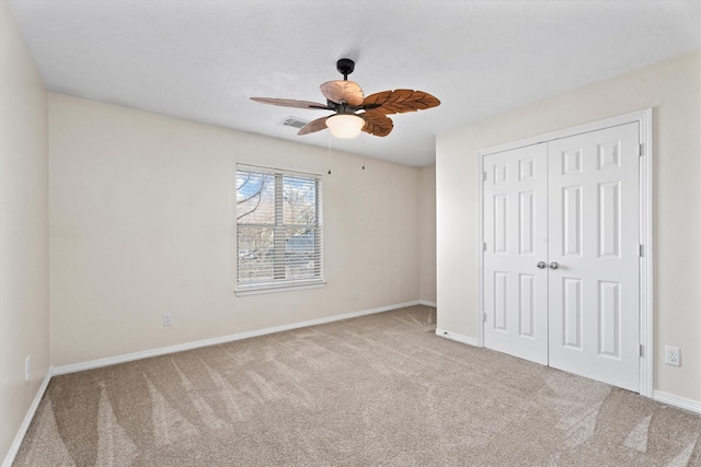 unfurnished bedroom featuring ceiling fan, light carpet, and a closet