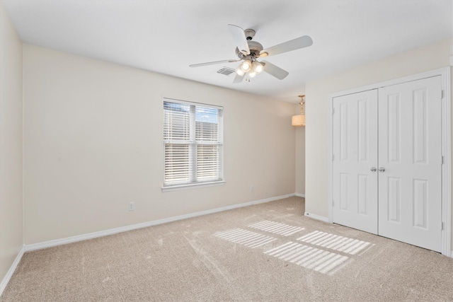 unfurnished bedroom featuring ceiling fan, a closet, and light carpet