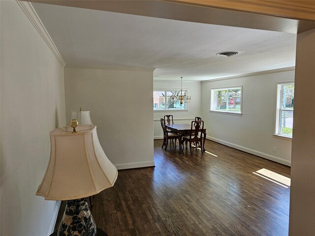 dining area featuring dark hardwood / wood-style floors, crown molding, and an inviting chandelier