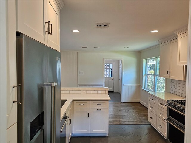 kitchen with white cabinets, appliances with stainless steel finishes, backsplash, and dark tile patterned flooring