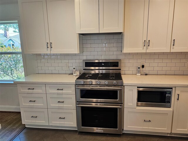 kitchen featuring light stone countertops, stainless steel appliances, white cabinetry, and tasteful backsplash