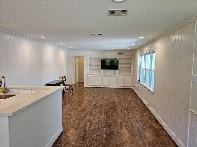 living room featuring dark hardwood / wood-style flooring, sink, built in features, and ornamental molding