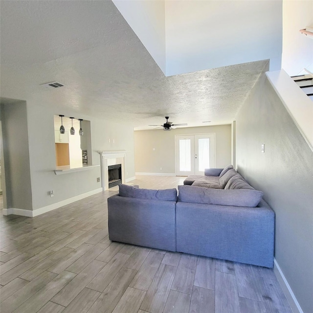 living room with ceiling fan, french doors, and a textured ceiling