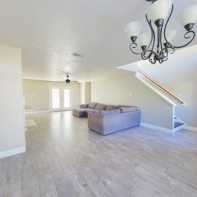 unfurnished living room featuring ceiling fan with notable chandelier, a textured ceiling, and light hardwood / wood-style flooring