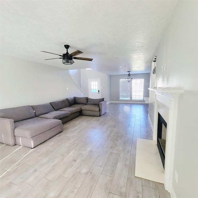 unfurnished living room featuring a textured ceiling and ceiling fan with notable chandelier