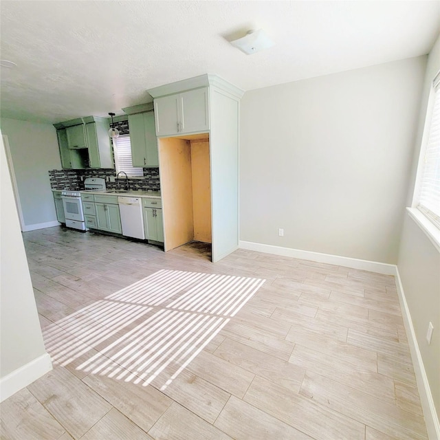 kitchen featuring white appliances, backsplash, sink, light hardwood / wood-style flooring, and green cabinetry