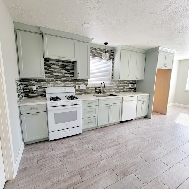 kitchen with decorative backsplash, sink, hanging light fixtures, and white appliances