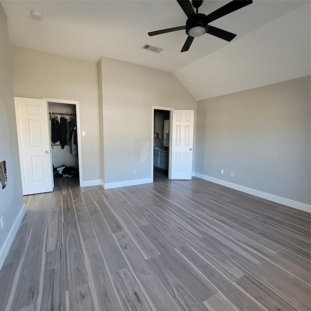 unfurnished bedroom with lofted ceiling, ceiling fan, a spacious closet, wood-type flooring, and a closet