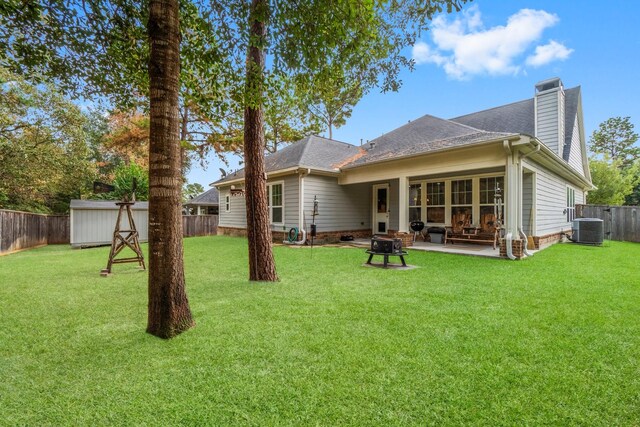 rear view of house featuring a yard, a patio, central AC unit, and a storage unit