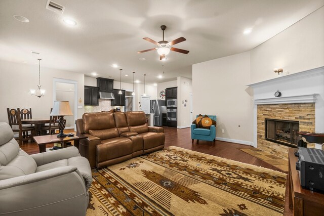 living room featuring ceiling fan with notable chandelier, dark hardwood / wood-style floors, and a fireplace