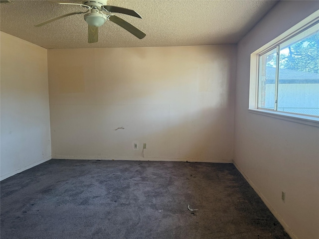 unfurnished room featuring a textured ceiling, dark carpet, and ceiling fan