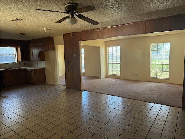 interior space featuring ceiling fan, sink, wood walls, a textured ceiling, and light tile patterned floors