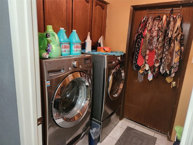 clothes washing area with cabinets, light tile patterned floors, and washer and dryer