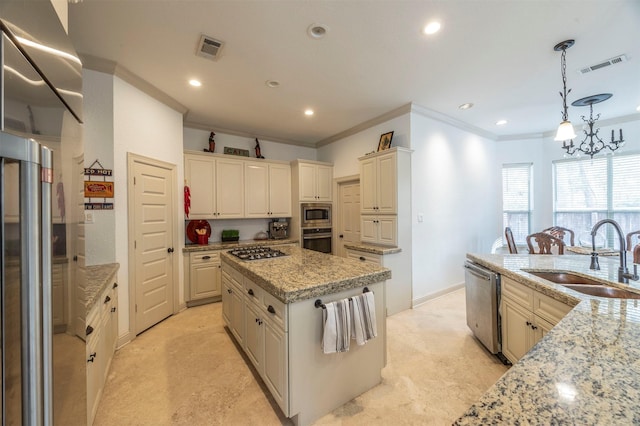 kitchen with sink, light stone counters, hanging light fixtures, appliances with stainless steel finishes, and a kitchen island