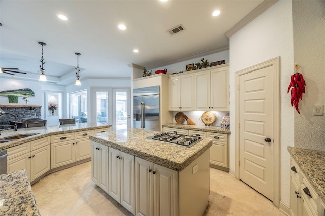 kitchen featuring sink, light stone counters, decorative light fixtures, a kitchen island, and stainless steel appliances