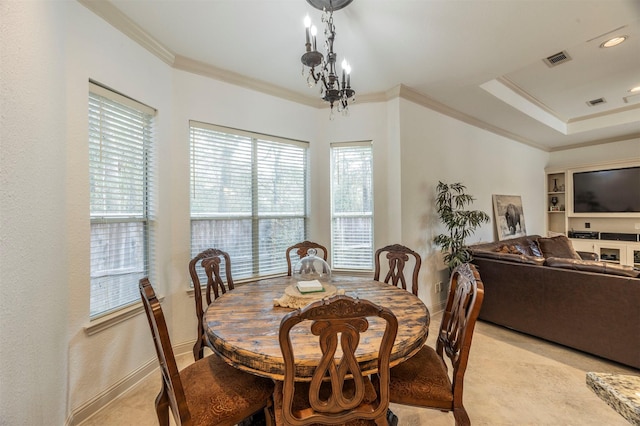 dining area featuring an inviting chandelier, a tray ceiling, and ornamental molding