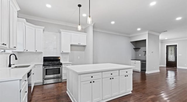 kitchen featuring white cabinetry, sink, a center island, backsplash, and appliances with stainless steel finishes