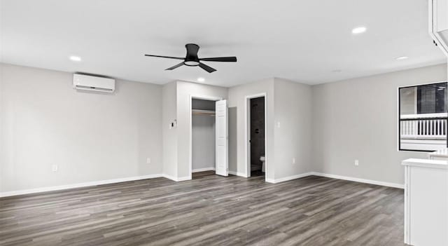 unfurnished bedroom with a wall mounted air conditioner, dark hardwood / wood-style floors, and ceiling fan