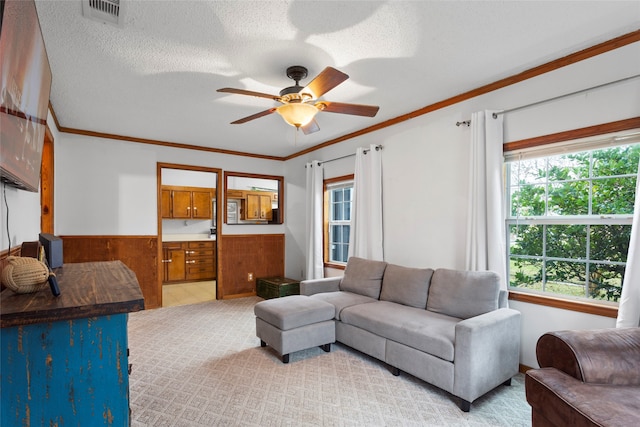 carpeted living room with a textured ceiling, plenty of natural light, and ceiling fan