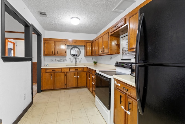 kitchen featuring a textured ceiling, black refrigerator, electric stove, and sink