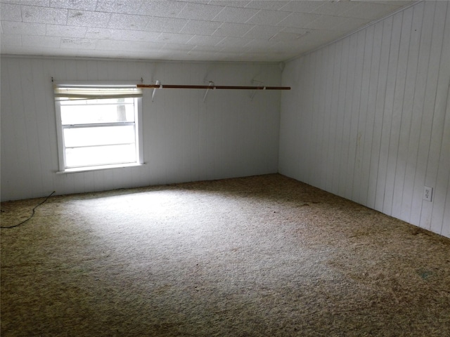 carpeted empty room featuring wooden walls