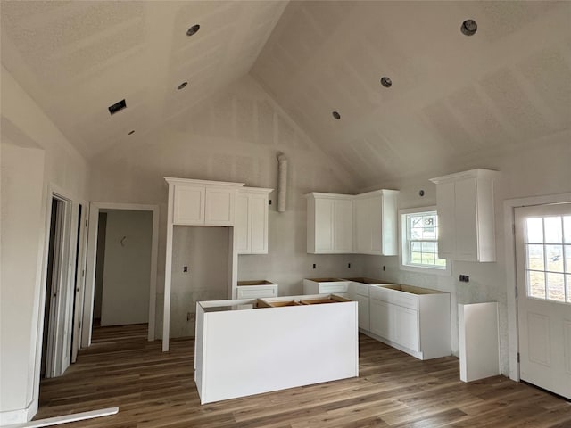 kitchen featuring hardwood / wood-style flooring, a center island, white cabinets, and high vaulted ceiling