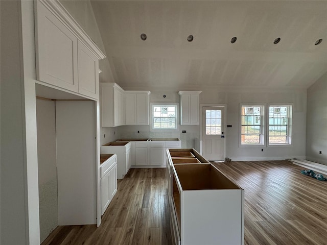 kitchen with white cabinetry, wood-type flooring, lofted ceiling, and a kitchen island