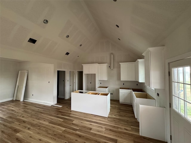 kitchen featuring white cabinetry, high vaulted ceiling, a kitchen island, and hardwood / wood-style flooring